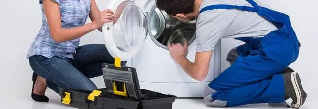 Washer repair technician inspecting a front-load washing machine with tools in Jacksonville, FL