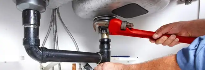Garbage disposal repair technician tightening the sink drain and disposal connection in Jacksonville, FL