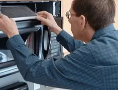 Appliance repair technician replacing a microwave vent filter in Jacksonville, FL
