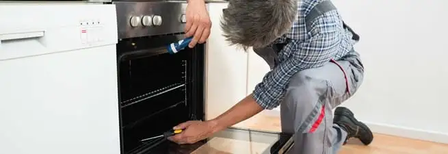 Oven repair technician inspecting and servicing an electric oven in Jacksonville, FL