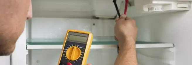 Refrigerator repair technician testing electrical components with a multimeter in Jacksonville, FL