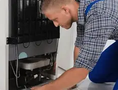 Refrigerator repair technician servicing the compressor and condenser area in Jacksonville, FL