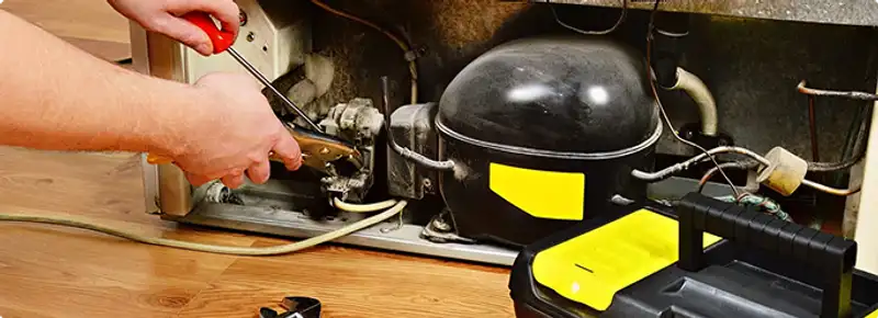 Refrigerator repair technician fixing the compressor and wiring in Jacksonville, FL